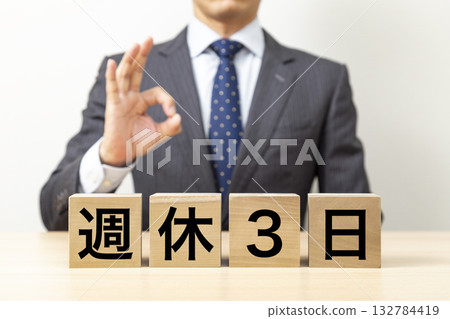 A businessman making an OK pose with a block that says "3 days off per week" 132784419