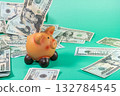 A piggy bank overflows with cash, symbolizing savings and financial growth, scattered on a vibrant green surface. 132784545