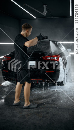 Professional washing luxury car with pressure hose during foam rinse Professional washing luxury car with pressure hose during foam rinse 132784556
