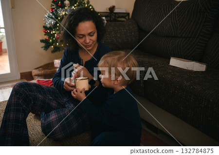 Mother And Child Share Warm Moment With Mug Near Christmas Tree In Cozy Living Room Mother And Child Share Warm Moment With Mug Near Christmas Tree In Cozy Living Room 132784875