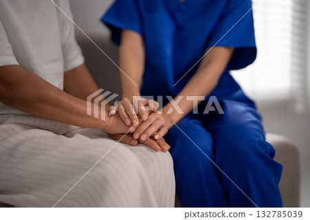 Adult Asian nurse caregiver hands provide comfort support to older Asian patient hands in healthcare medical senior living facility Adult Asian nurse caregiver hands provide comfort support to older Asian patient hands in healthcare medical senior living facility 132785039