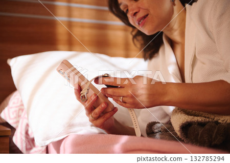 Woman In Bathrobe Using Smartphone In Bed With Cozy Blanket And Pillow Woman In Bathrobe Using Smartphone In Bed With Cozy Blanket And Pillow 132785294