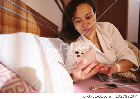 Relaxed Woman In White Robe Using Smartphone In Bed, Cozy Morning Home Scene Relaxed Woman In White Robe Using Smartphone In Bed, Cozy Morning Home Scene 132785297