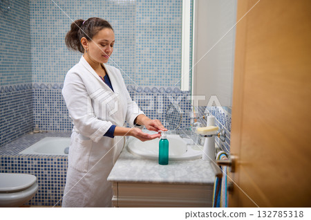 Woman In White Bathrobe Washing Hands At Bathroom Sink With Blue Mosaic Tiles 132785318