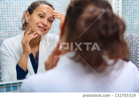 Woman Looks in Mirror Skincare Routine, Reflecting Smiles, Self Care in Bathroom 132785329