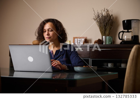 Woman Working On Laptop At Home Kitchen Table, Focused On Screen, Quiet Morning Woman Working On Laptop At Home Kitchen Table, Focused On Screen, Quiet Morning 132785333