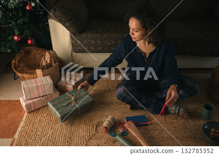 Woman Wrapping Gifts At Home By Christmas Tree, Cozy Holiday Scene 132785352