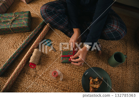 Person Wrapping A Gift On The Floor, Home Holiday Crafting Scene With Gift Wrap Person Wrapping A Gift On The Floor, Home Holiday Crafting Scene With Gift Wrap 132785363