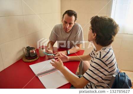 Casual Indoor Meeting Between Two Men At Red Table With Notebook And Coffee Casual Indoor Meeting Between Two Men At Red Table With Notebook And Coffee 132785627