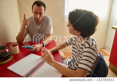 Two Men Discussing With Phone At Red Table In Bright Kitchen, Casual Study Session 132785631