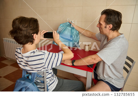 Father And Son Photograph Blue Grocery Bag At Red Table In Kitchen Father And Son Photograph Blue Grocery Bag At Red Table In Kitchen 132785655