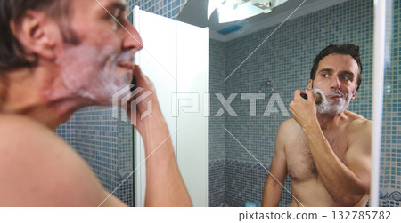 Man Shaving in Front of Bathroom Mirror, Foam on Face, Quiet Morning Grooming Man Shaving in Front of Bathroom Mirror, Foam on Face, Quiet Morning Grooming 132785782