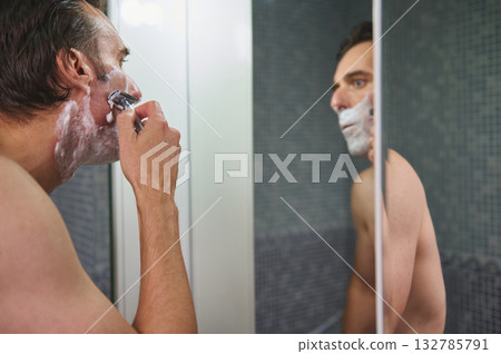 Man Shaving in Bathroom Mirror, Morning Grooming Routine, Foam and Razor Man Shaving in Bathroom Mirror, Morning Grooming Routine, Foam and Razor 132785791
