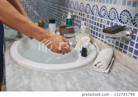 Man Shaving at Bathroom Sink With Razor, Brush, and Soap on Marble Countertop Man Shaving at Bathroom Sink With Razor, Brush, and Soap on Marble Countertop 132785796