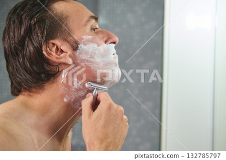 Man Shaving in Bathroom With Foam and Razor - Close Profile View Man Shaving in Bathroom With Foam and Razor - Close Profile View 132785797