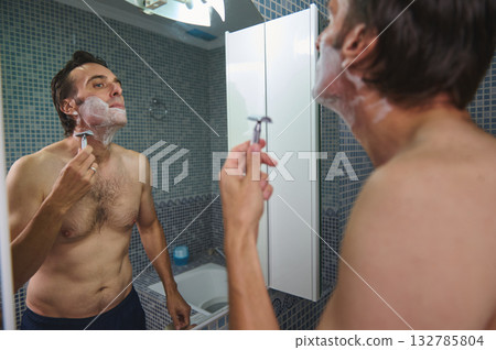 Man Shaving in Bathroom Mirror, Morning Grooming Routine with Shaving Foam 132785804