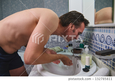 Man Washing Face At Bathroom Sink In Studio Shot For Grooming And Hygiene Concept 132785811