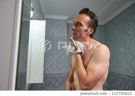 Man In Bathroom Looking At Mirror After Shower With Towel Over Shoulder Man In Bathroom Looking At Mirror After Shower With Towel Over Shoulder 132785822