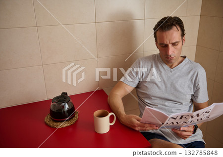 Man Reading Newspaper At Red Table With Coffee Cup And Kettle In Kitchen Setting Man Reading Newspaper At Red Table With Coffee Cup And Kettle In Kitchen Setting 132785848