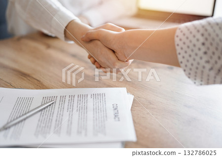 Business people shaking hands above contract papers just signed on the wooden table, close up. Lawyers at meeting. Teamwork, partnership, success concept Business people shaking hands above contract papers just signed on the wooden table, close up. Lawyers at meeting. Teamwork, partnership, success concept 132786025