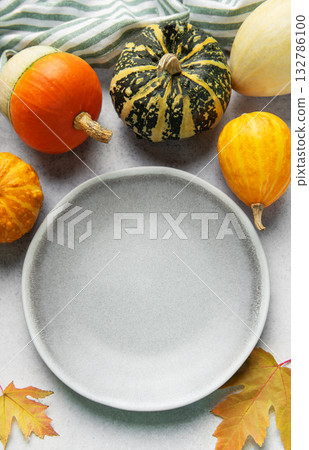Empty plate surrounded by autumn gourds and leaves 132786100