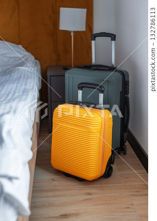 Luggage standing beside bed in modern hotel room 132786113
