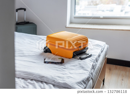Orange suitcase on hotel bed ready for travel 132786118