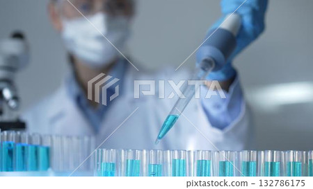Woman scientist researcher using a micropipette to fill up test tubes with a blue liquid in laboratory setting, closeup view. Medicine and science concept 132786175