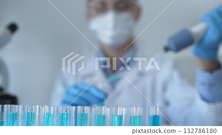 Laboratory tubes are in focus, closeup view. Female scientist researcher is using a micropipette at the lab background. Medicine and science 132786180