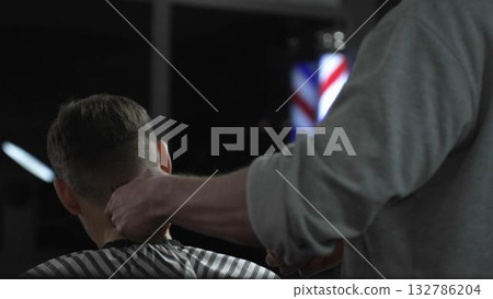 Skilled barber trimming client's hair with electric razor, creating precise contemporary hairstyle inside sleek urban barbershop setting Skilled barber trimming client's hair with electric razor, creating precise contemporary hairstyle inside sleek urban barbershop setting 132786204