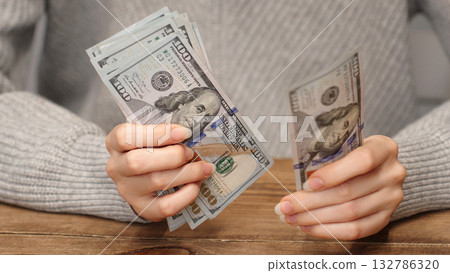 Woman counting 100 US dollar bills. Cash calculation concept for personal finance, salary or savings planning. Ideal for financial background or educational content. Woman's hands holds dollar bills. Woman counting 100 US dollar bills. Cash calculation concept for personal finance, salary or savings planning. Ideal for financial background or educational content. Woman's hands holds dollar bills. 132786320