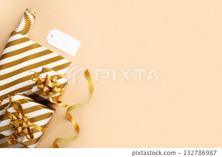 Gift wrapping items. White and gold striped paper, ribbon, gift tag. Copy space Gift wrapping items. White and gold striped paper, ribbon, gift tag. Copy space 132786987