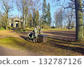 A tractor is collecting leaves in an autumn park. 132787126