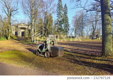 A tractor is collecting leaves in an autumn park. A tractor is collecting leaves in an autumn park. 132787126