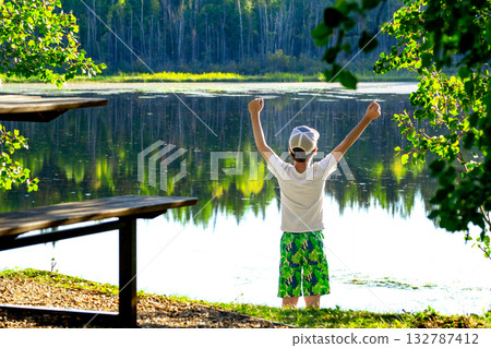 Teen boy at the little forest lake in hot summer day. 132787412