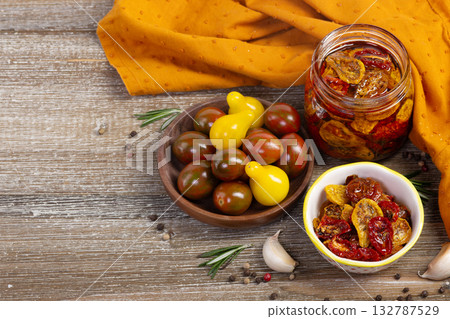 Dried cherry tomatoes in a jar and plate with ingredients around. Dried cherry tomatoes in a jar and plate with ingredients around. 132787529