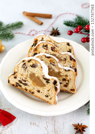 Traditional German Christmas stollen with marzipan, raisins and powdered sugar on a festive table.  132787568