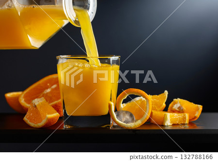 Glass of orange juice with ice on a black background. 132788166
