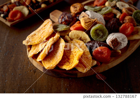 Dried mango slices, tropical fruits, nuts, and raisins on a wooden table. 132788167