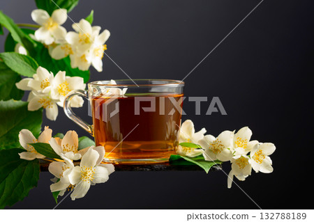 Cup of jasmine tea and fresh jasmine flowers on a black background. 132788189