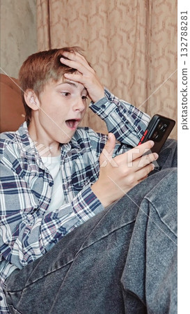 Caucasian handsome guy with phone, is emotion of winning. Amazed handsome teenager receiving sms message offer opportunity. happy man reading good news on smartphone. 132788281