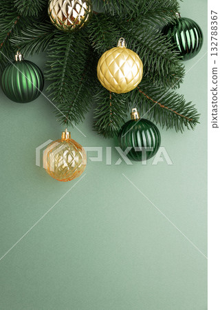 Green and Gold Christmas Ornaments Hanging on Pine Branches over Muted Green Background 132788367