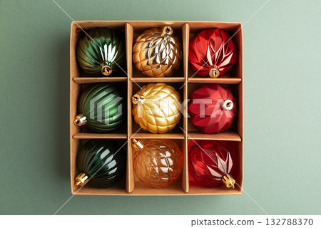 Box of Christmas Ornaments in Festive Colors on Green Background 132788370