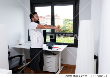 Young caucasian male stretching in home office for a relaxed work environment 132788421