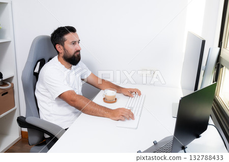 Young caucasian male working at desk with coffee in modern office Young caucasian male working at desk with coffee in modern office 132788433