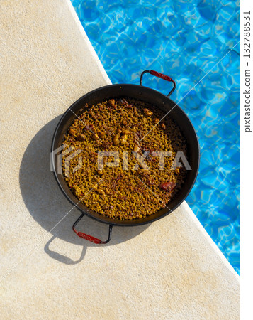 Spanish Paella Beside a Swimming Pool on a Sunny Day Spanish Paella Beside a Swimming Pool on a Sunny Day 132788531