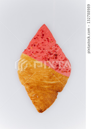 Golden croissant with pink strawberry glaze and dried berry crumbs on white background 132788989