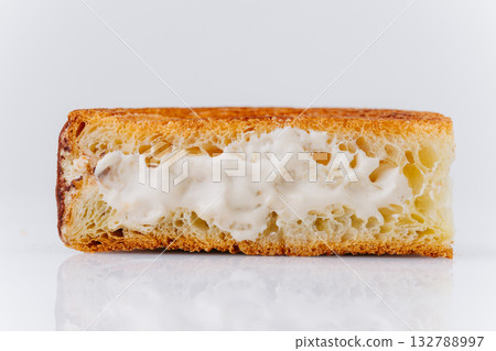 Close-up of airy croissant slice filled with creamy vanilla tiramisu cream on white background Close-up of airy croissant slice filled with creamy vanilla tiramisu cream on white background 132788997