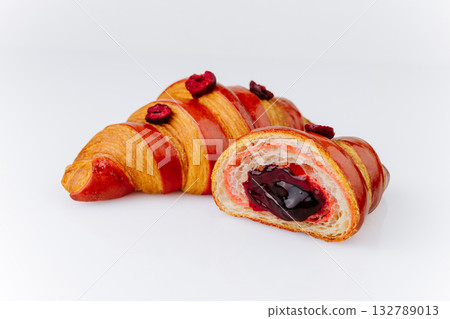 Cut red croissant with berry filling and dried raspberries, elegant modern pastry on white 132789013