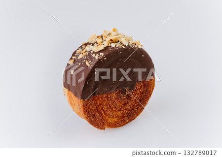 Round croissant pastry coated with chocolate glaze and crushed hazelnuts on white background Round croissant pastry coated with chocolate glaze and crushed hazelnuts on white background 132789017